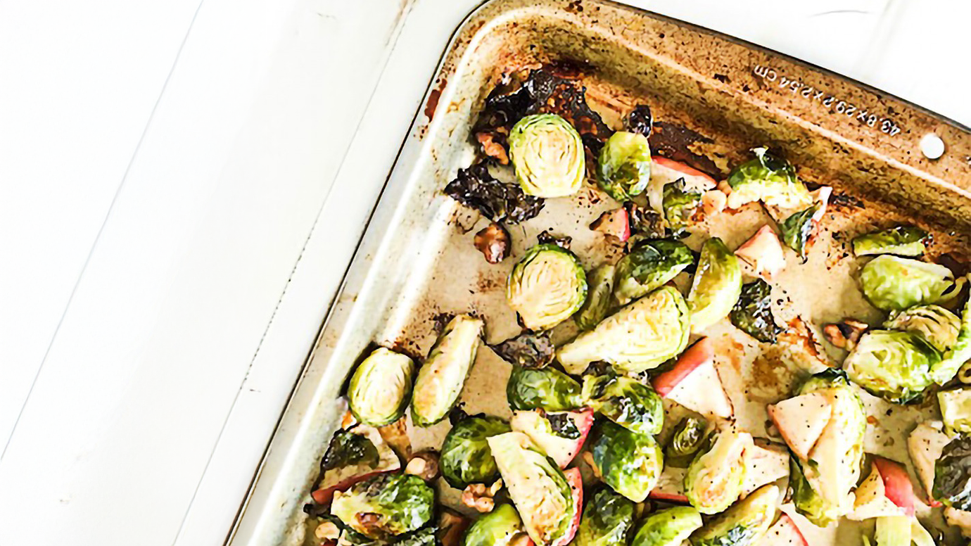 Brussels sprouts with apples and walnuts on a sheet pan.