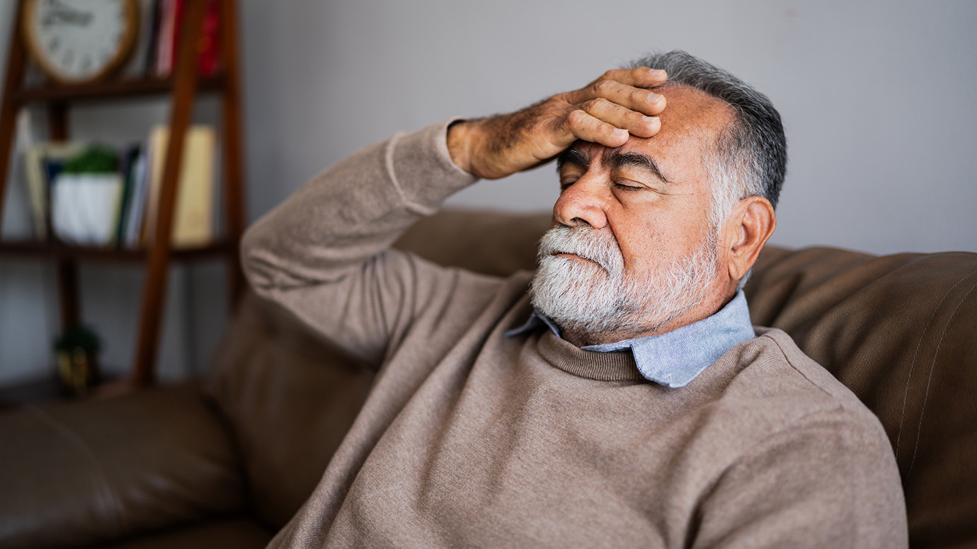 Tired man holds forehead.