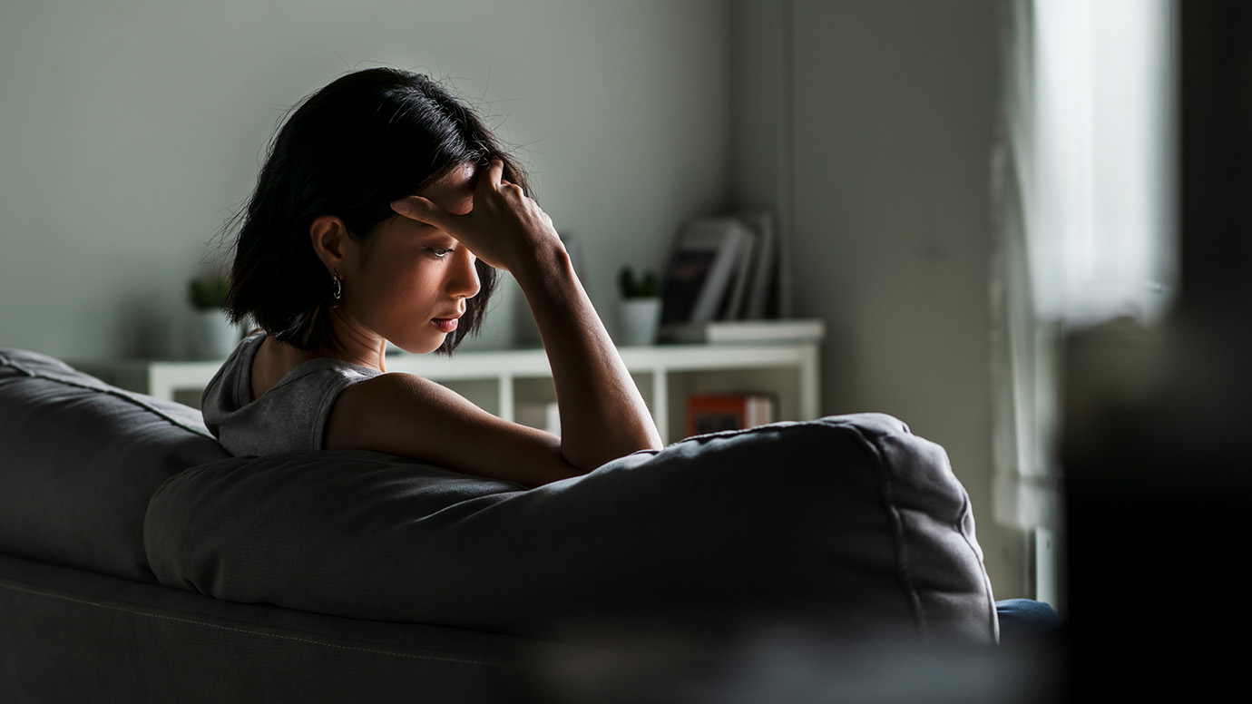 Woman holds her forehead while looking sad.