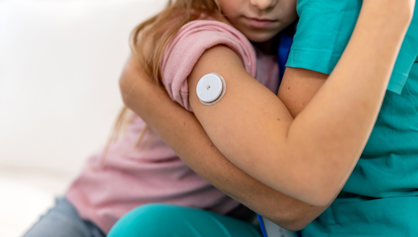 Person wearing CGM hugs another person.