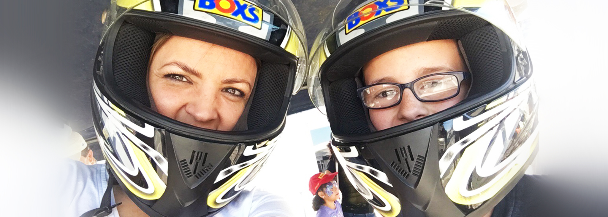 Woman, left, and young boy, right pose in motocross helmets.