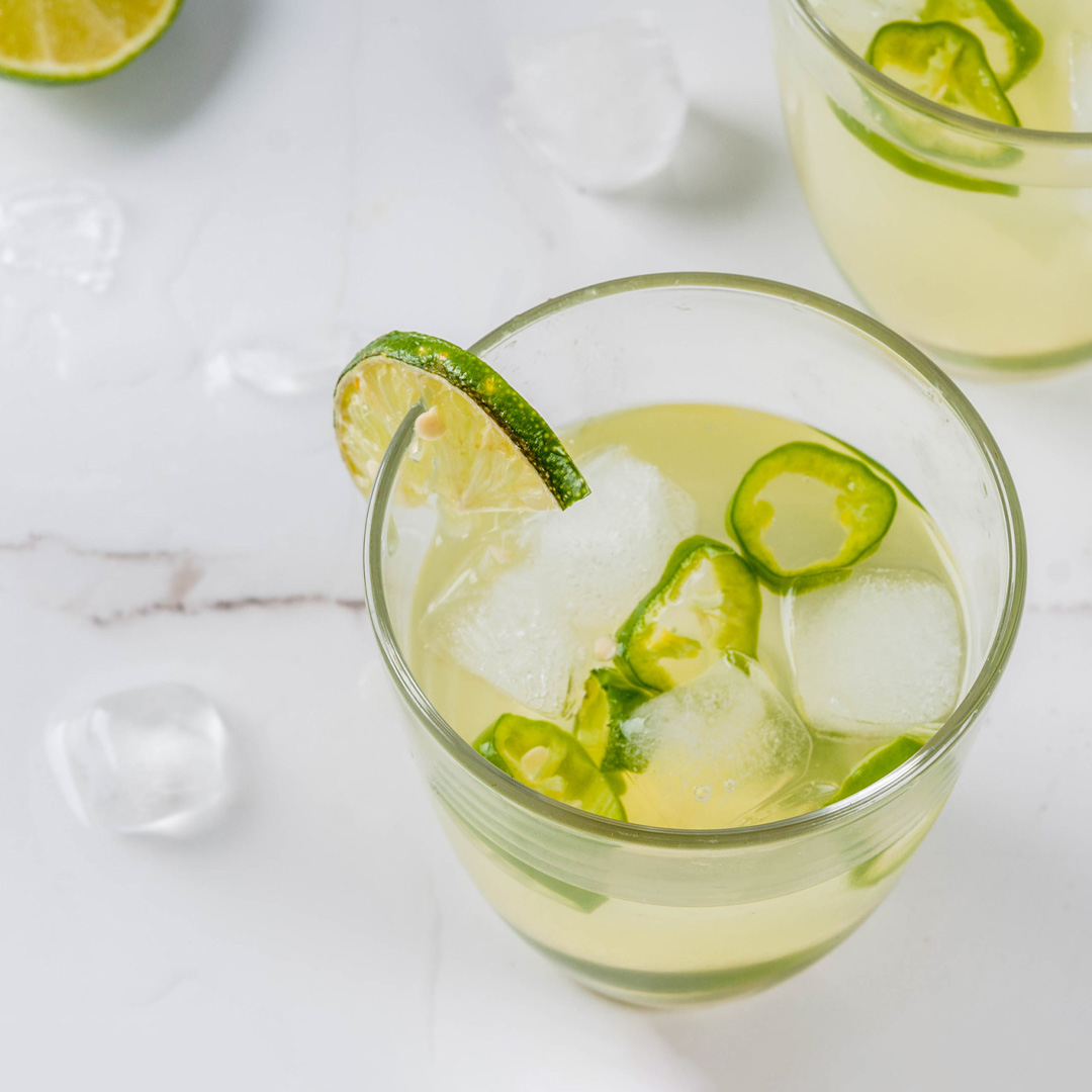 Spicy margarita in a glass garnished with lime.