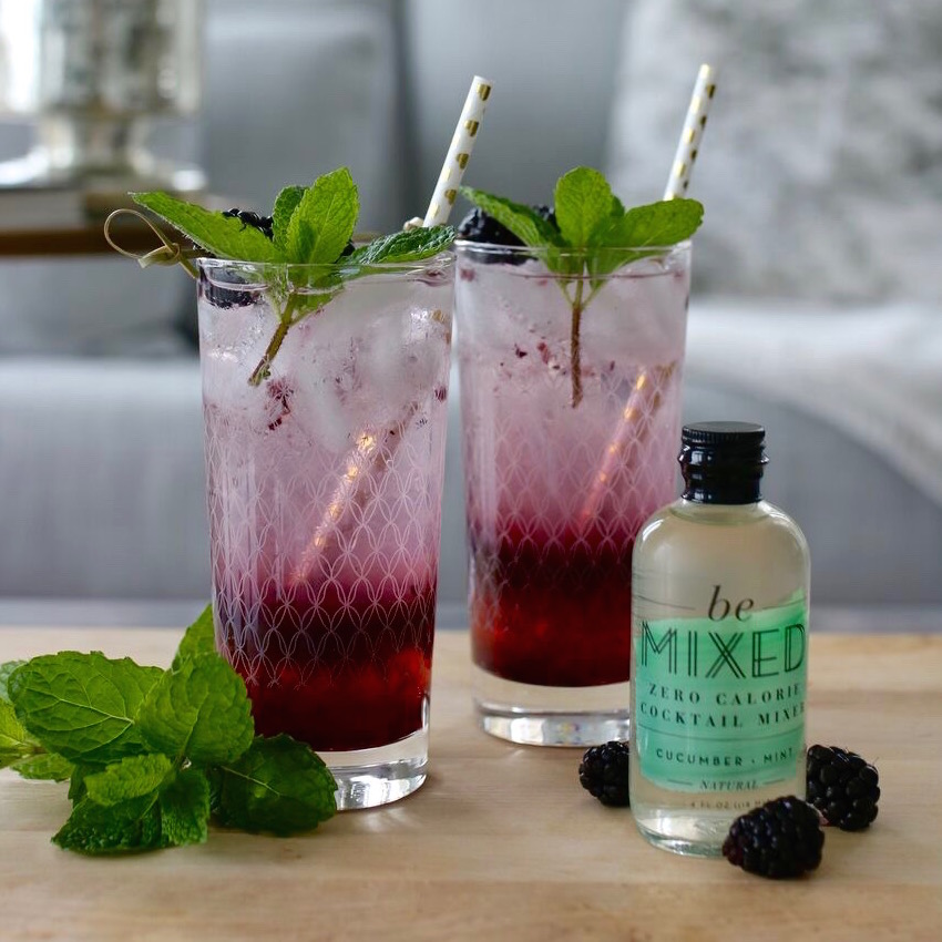 Two blackberry mojitos garnished with mint.