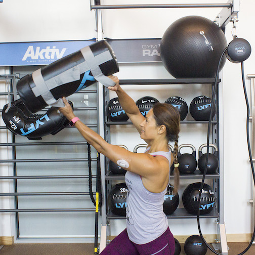 Christel Oerum lifts a weight over her head, she has a Continuous Glucose Monitor on her upper arm.