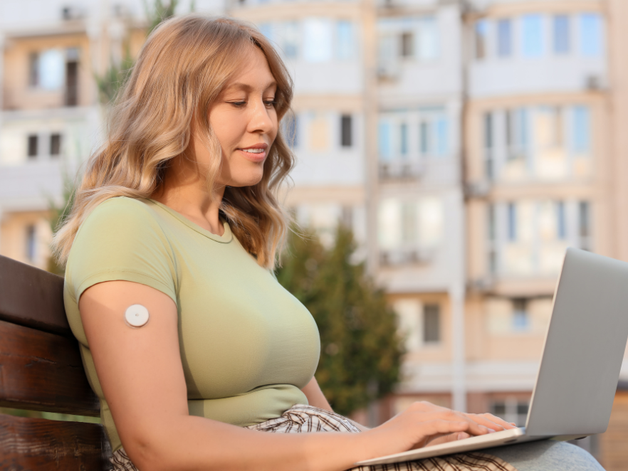 Woman wearing CGM on laptop