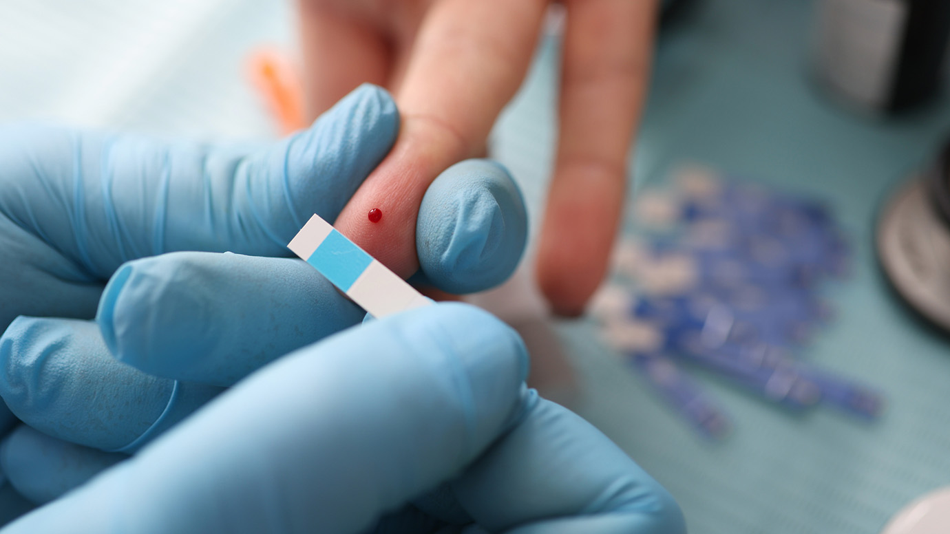 A finger and blood glucose test strip.