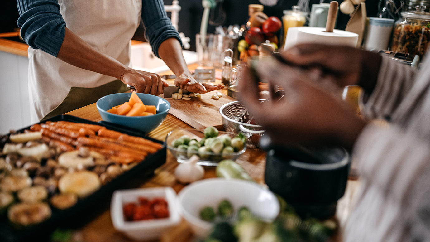 People gather over a table full of snacks.