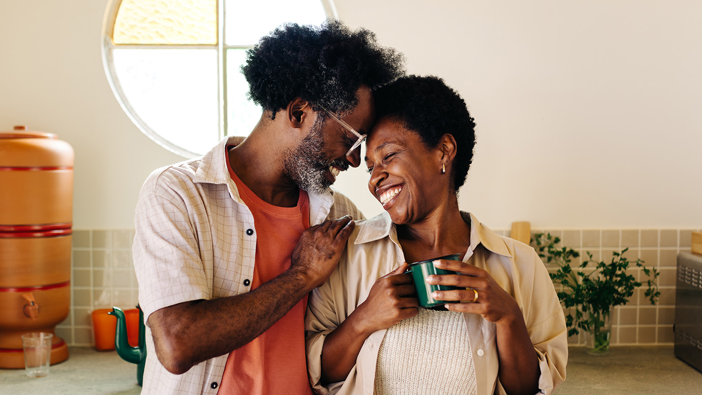 A couple embraces in the kitchen.