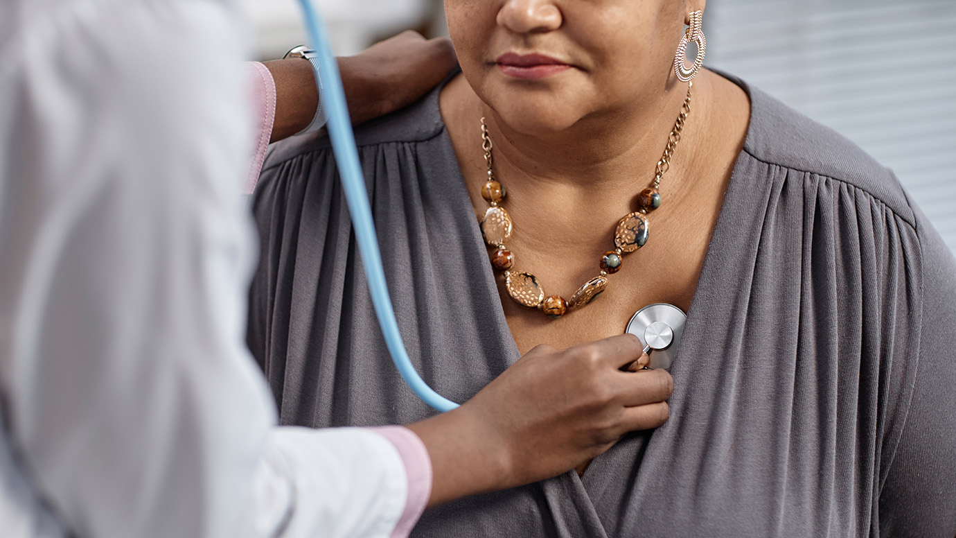 Doctor uses a stethoscope on a woman.