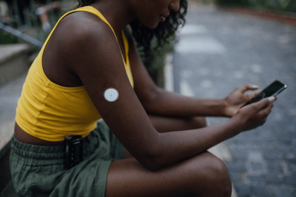 Woman wearing a CGM checks phone.