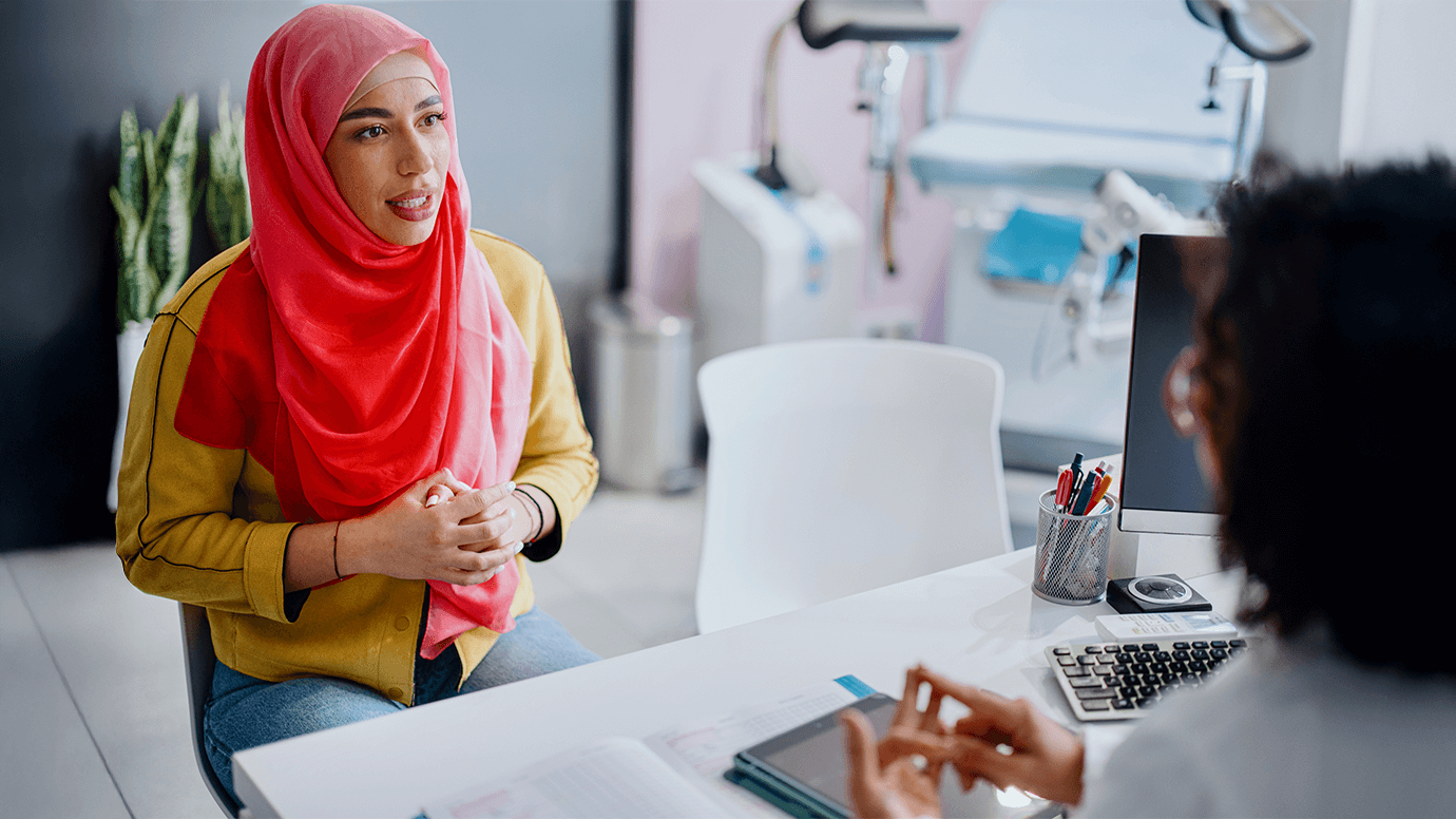 Woman in hijab sit across from a medical professional.